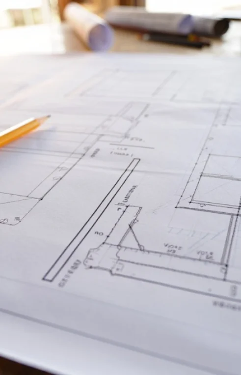 Detailed architectural blueprints and construction shop drawings in Alabama laid out on a table with a pencil and scale ruler for engineering review.